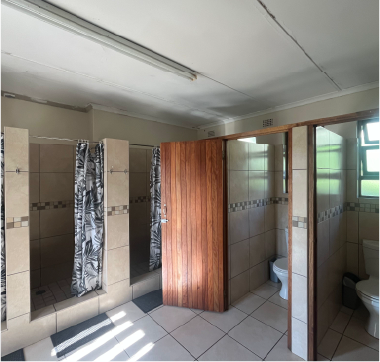 Clean tiled bathroom at Camp Anerley with showers, toilets, and wooden doors.