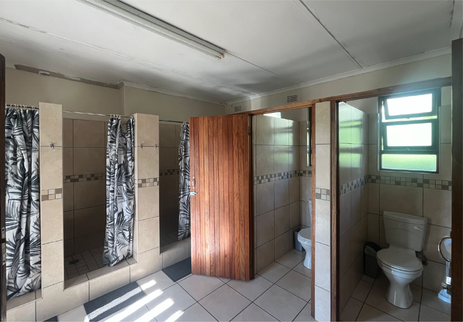 Clean and modern bathroom facilities at Camp Anerley with tiled showers, toilets, and privacy curtains.