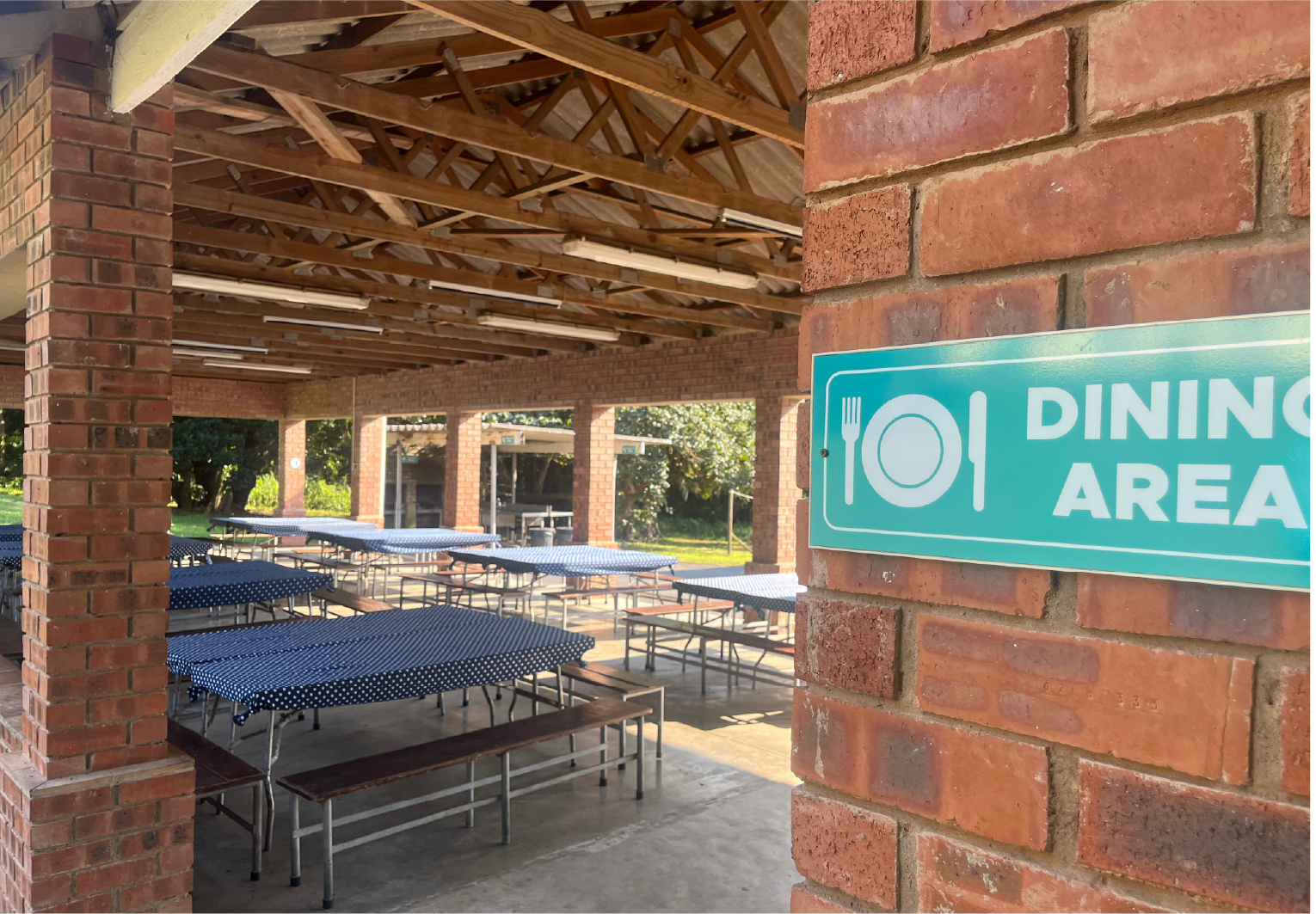 Camp Anerley’s open-air dining area with long tables and benches covered in blue polka-dot cloths, ready for mealtime.