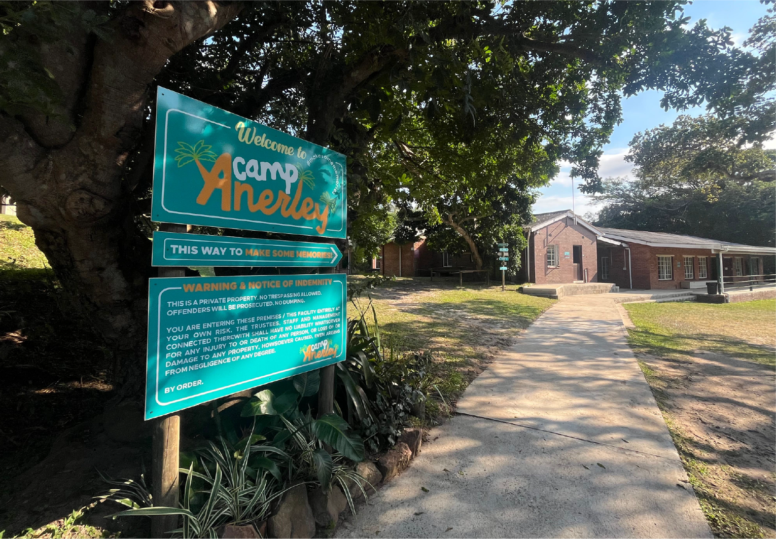 Entrance sign welcoming visitors to Camp Anerley on the KwaZulu-Natal South Coast, with trees and camp buildings in the background.