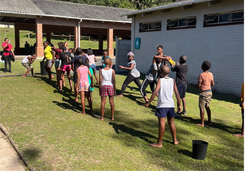 Children playing a fun outdoor water game at Camp Anerley, laughing and enjoying the sunshine.