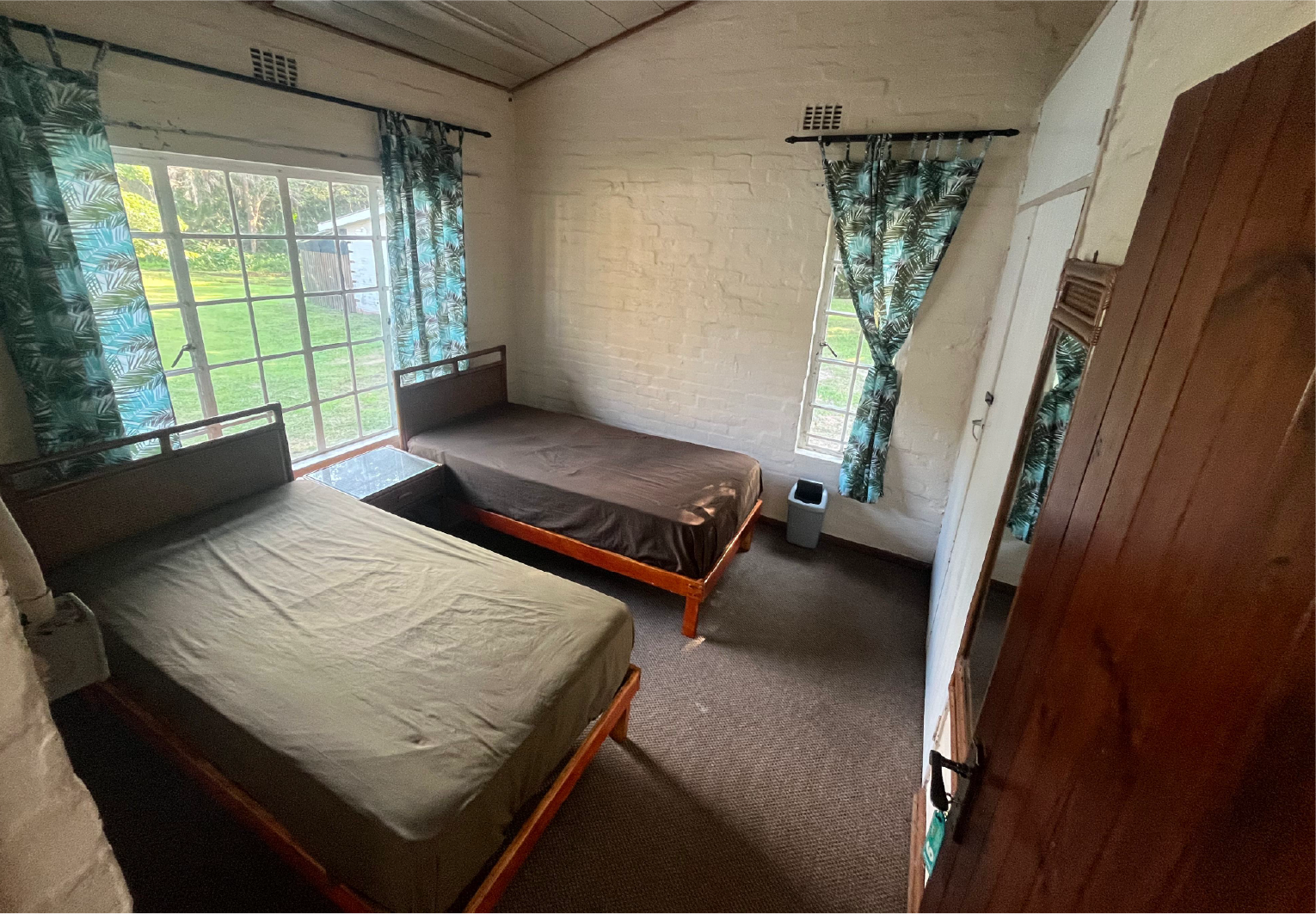 Private leaders’ accommodation at Camp Anerley featuring two single beds, natural light, and views of the garden.