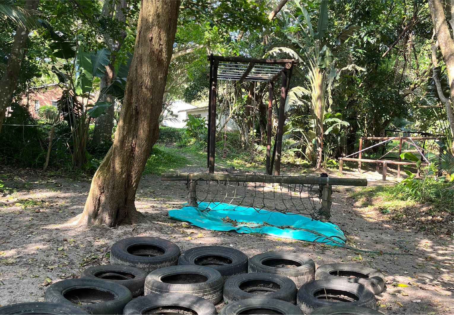 Outdoor obstacle course at Camp Anerley featuring tyres, ropes, and climbing challenges surrounded by trees.