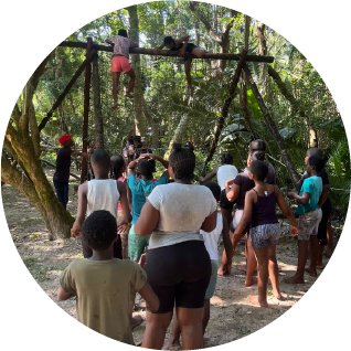 Children participating in an outdoor obstacle activity at Camp Anerley, surrounded by trees and nature.