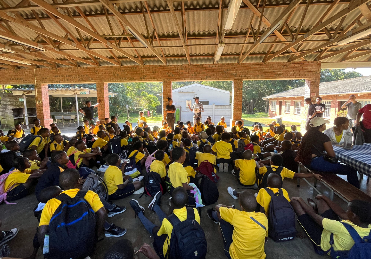 Large group of school children in yellow uniforms gathered for an educational session at Camp Anerley’s covered dinning area.