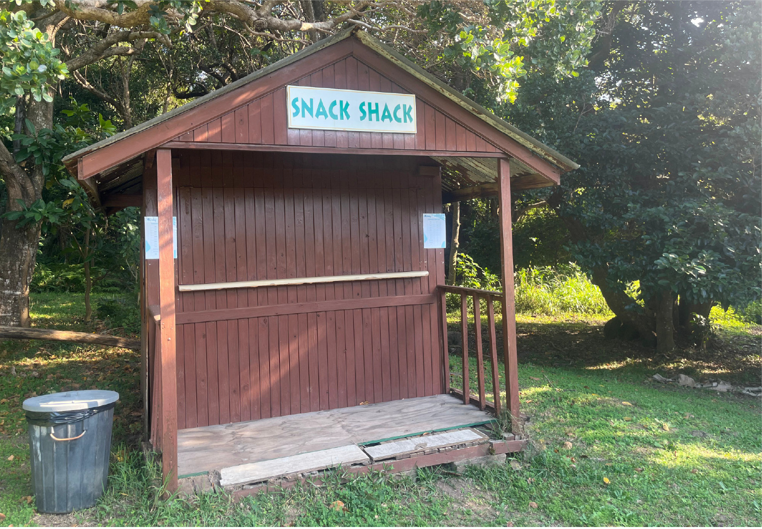The Snack Shack at Camp Anerley, a small wooden kiosk surrounded by trees, ready to serve campers treats and refreshments.
