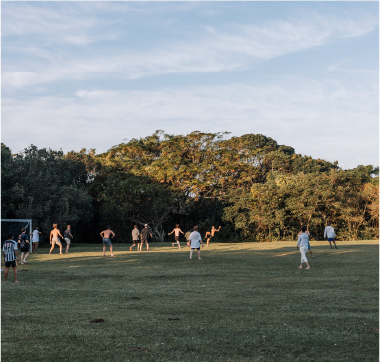 Campers playing soccer on a large grassy field surrounded by trees at Camp Anerley.